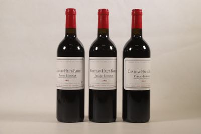 trois bouteilles de vin rouge sont alignées sur une surface blanche