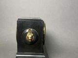 a small black clock with a gold lion head on it