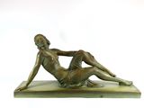bronze statue of a woman laying on her stomach on a marble base