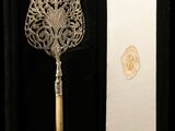 an ornate silver spoon with a wooden handle in a black box