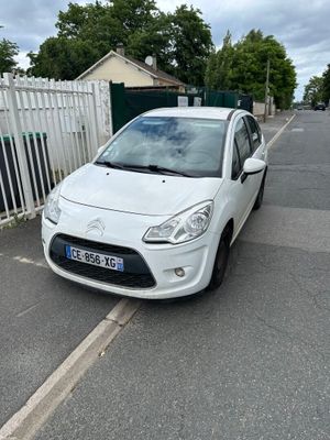 la petite voiture blanche est garée sur le bord de la route