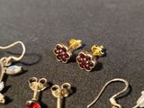 several pairs of earrings are displayed on a black surface