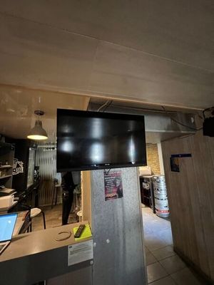 une télévision à écran plat fixée au-dessus d'un réfrigérateur dans une cuisine