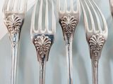 four forks and a knife on a plate on a table