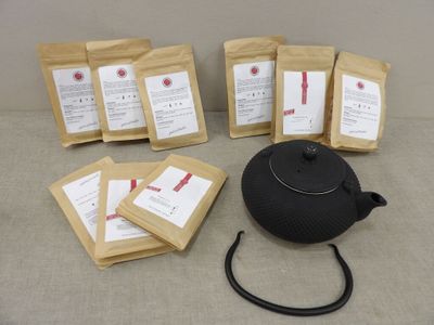 une théière noire posée à côté d'un paquet de sachets de thé