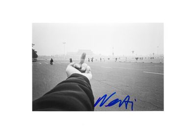 signed photo of a person holding their thumb up in the middle of a parking lot