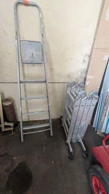 une échelle appuyée contre un mur, à côté d'une pile de bagages