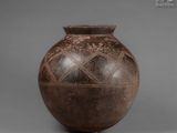 an old brown vase sitting on top of a table next to a gray wall