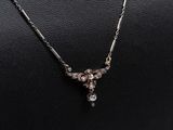 un collier en argent orné d'un pendentif en diamant, porté par un mannequin noir