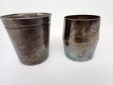 two metal cups sitting next to each other on a table