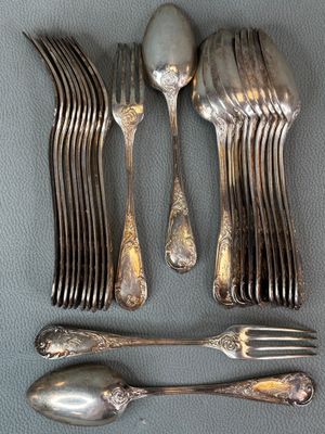 a lot of silver spoons and forks laid out on a table