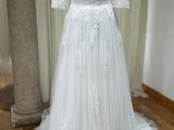 une robe de mariée posée sur un mannequin devant un vase de fleurs
