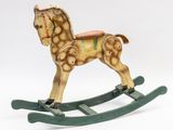 a small wooden rocking horse with a saddle on it ' s back