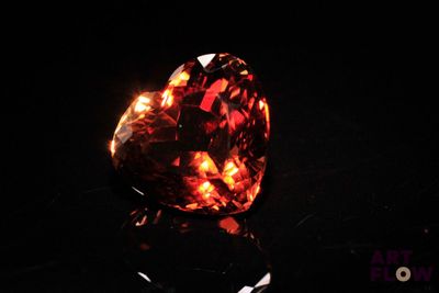 a close up of a heart shaped red diamond on a black surface