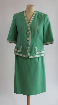 un tailleur-jupe vert sur un mannequin, devant un fond blanc