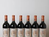 six bottles of red wine lined up on a wooden table