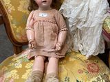 a doll sitting on a chair with a dress on it