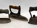 trois objets anciens en fonte posés sur un plan de travail blanc