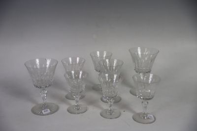 six clear wine glasses are lined up on a white surface