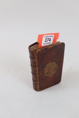 un petit livre marron sur lequel est accrochée une étiquette rouge