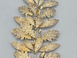 broche en forme de feuille plaquée or, ornée d'un nœud et d'un ruban