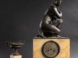une photo représentant une statue de femme assise sur une table, à côté d'une horloge