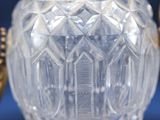 a clear glass vase with a gold handle on a table