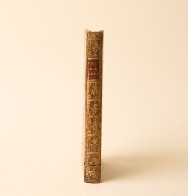un vieux livre posé sur une table à côté d'un mur blanc