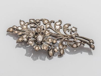 un gros plan d'une broche en argent ornée de perles sur un fond blanc