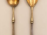 two spoons and a fork on a white surface