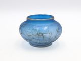 a blue glass vase with a gold rim on a white surface