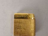 a close up of a gold lighter on a white surface