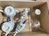 quatre théières et deux tasses dans une boîte en carton