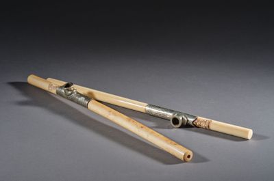 une paire de baguettes en bambou avec un manche en argent sur un fond gris