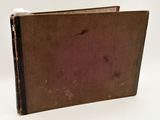an old book sitting on top of a white table next to a white wall