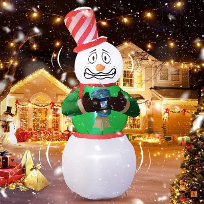 un bonhomme de neige gonflable muni d'un appareil photo, devant une maison