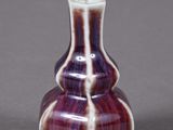 a purple and white vase sitting on a gray surface