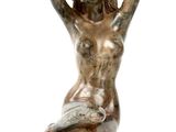 statue of a woman sitting on a rock with her hands behind her head
