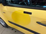 a yellow car that has a sticker on the door