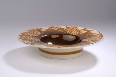 un bol marron et blanc posé sur une table blanche