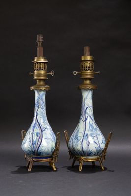 paire de vases bleus et blancs avec des anses en laiton, posés sur des socles