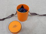a small orange bucket with a black tie and a small orange box with a black tie