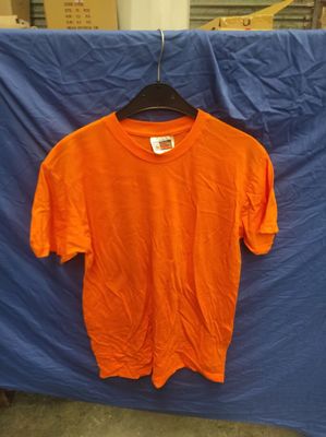un t-shirt orange suspendu à un drap bleu devant un drap bleu