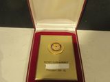 a gold medal in a red box on a white table