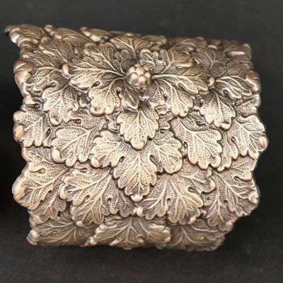 boîte plaquée argent, ornée de fleurs et de feuilles sur un fond noir
