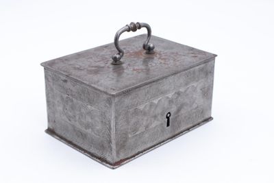 une vieille boîte en métal munie d'un cadenas, posée sur une surface blanche