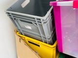 a pile of boxes and bins sitting on top of a wooden floor