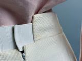 a close up of a person wearing a pink shirt and white pants