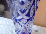 a blue glass vase sitting on a table with a pink flower