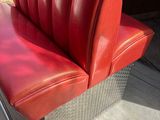 a red bench with a red seat and a red car in the background